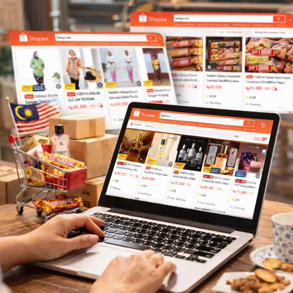 Paparan Shopee Indonesia di laptop dengan hasil carian produk termasuk coklat dan perfume, bersama barang belian seperti kotak dan troli mini menunjukkan proses pembelian dan penghantaran ke Malaysia